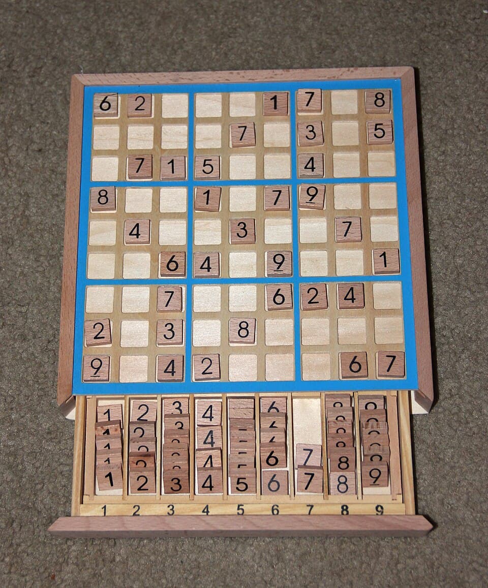 Wooden Sudoku board game with numbered tiles and a blue 9x9 grid